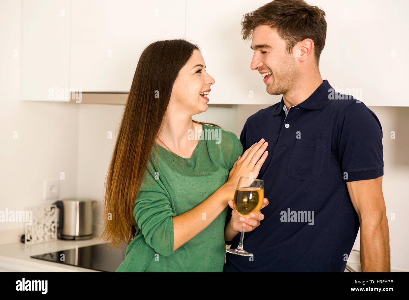Junges Paar auf der Küche bei einem Glas Weißwein Stockfoto
