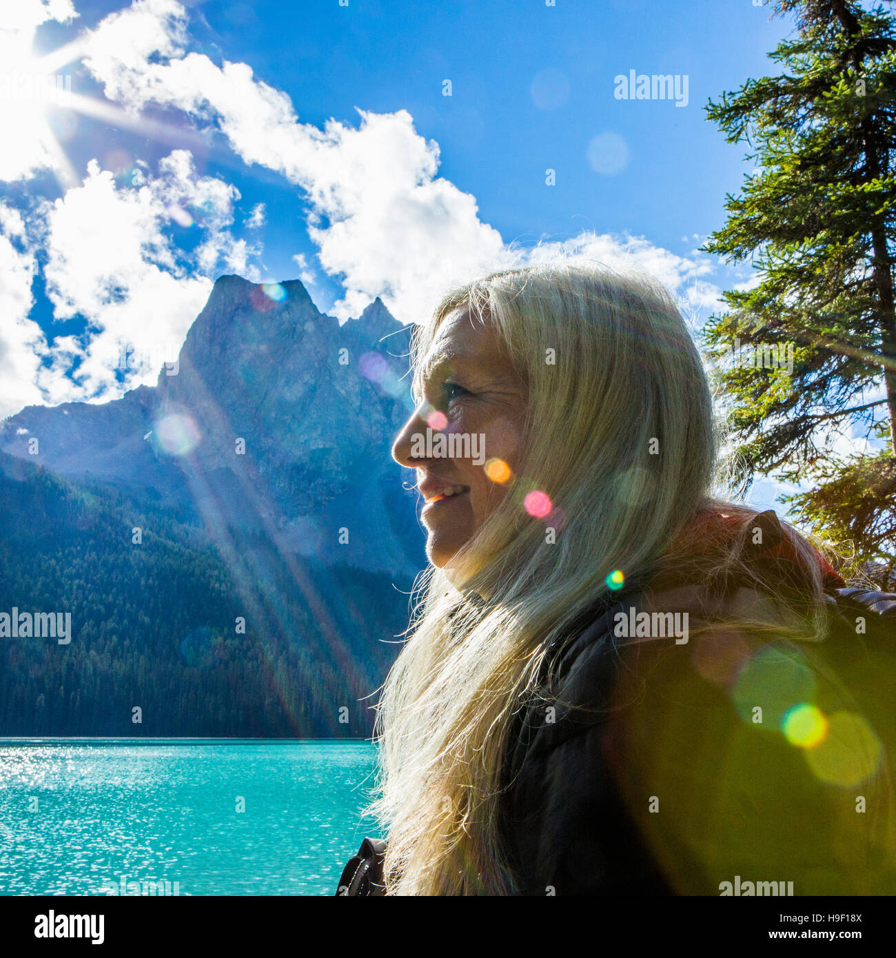 Sonnenstrahlen auf Gesicht der kaukasischen Frau am Bergsee Stockfoto