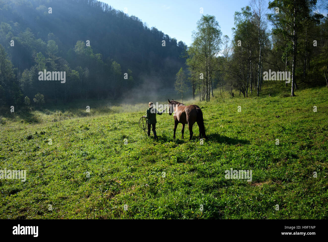 Kaukasische Mädchen Walking Pferd im Feld Stockfoto