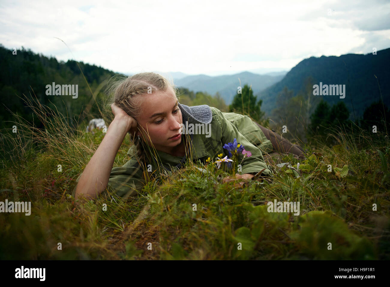 Kaukasische Mädchen halten Wildblumen Verlegung in Rasen auf Hügel Stockfoto