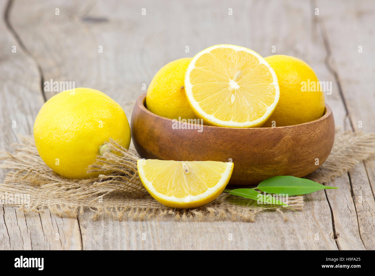 frische Zitronen in einer Schüssel auf hölzernen Hintergrund Stockfoto
