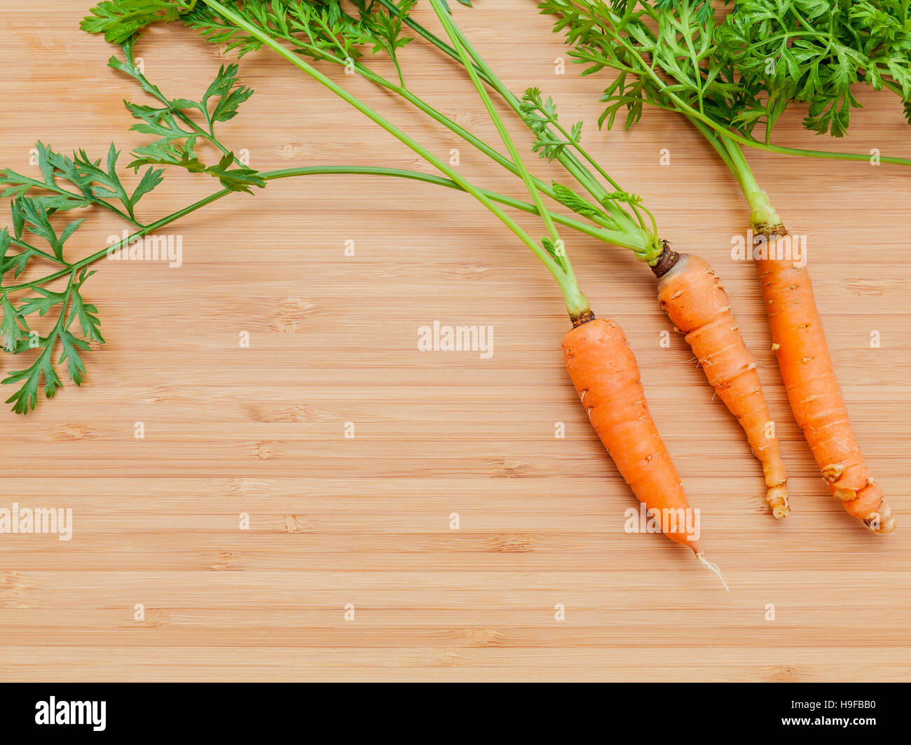 Frische Karotten Haufen auf Holztisch. Rohe frische Karotten mit Endstück Stockfoto