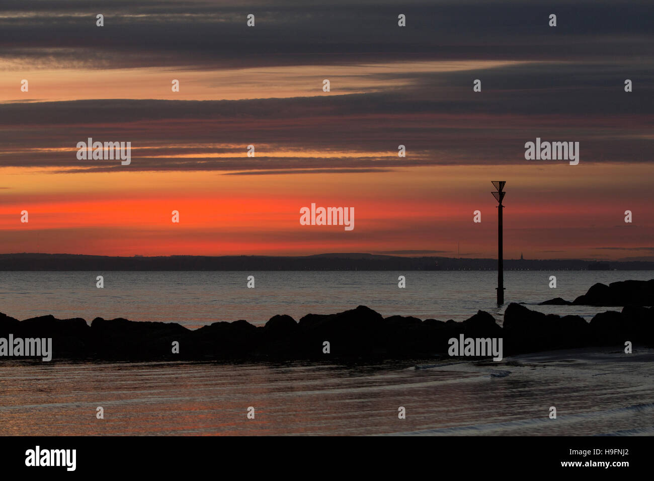 Strand-Marker im Meer gegen einen lebendigen Sonnenuntergang Sign. Ruhige See und Land jenseits. Bunten Himmel vor Hayling Island Hampshire Stockfoto