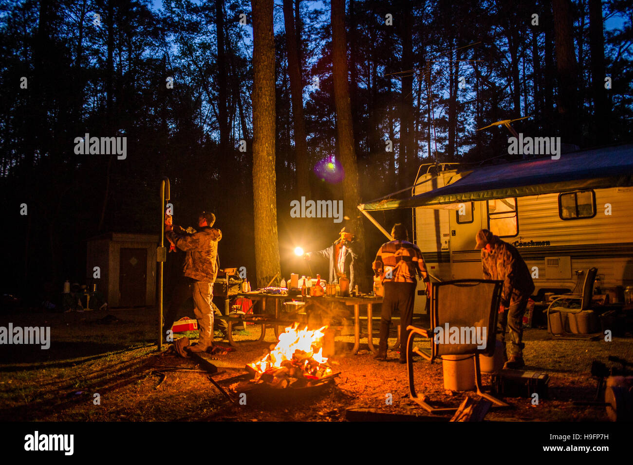 Ein Wels Hände an einem Haken um einen Campingplatz, wo ein Feuer brennt hell und einheimischen Bier trinken. Stockfoto