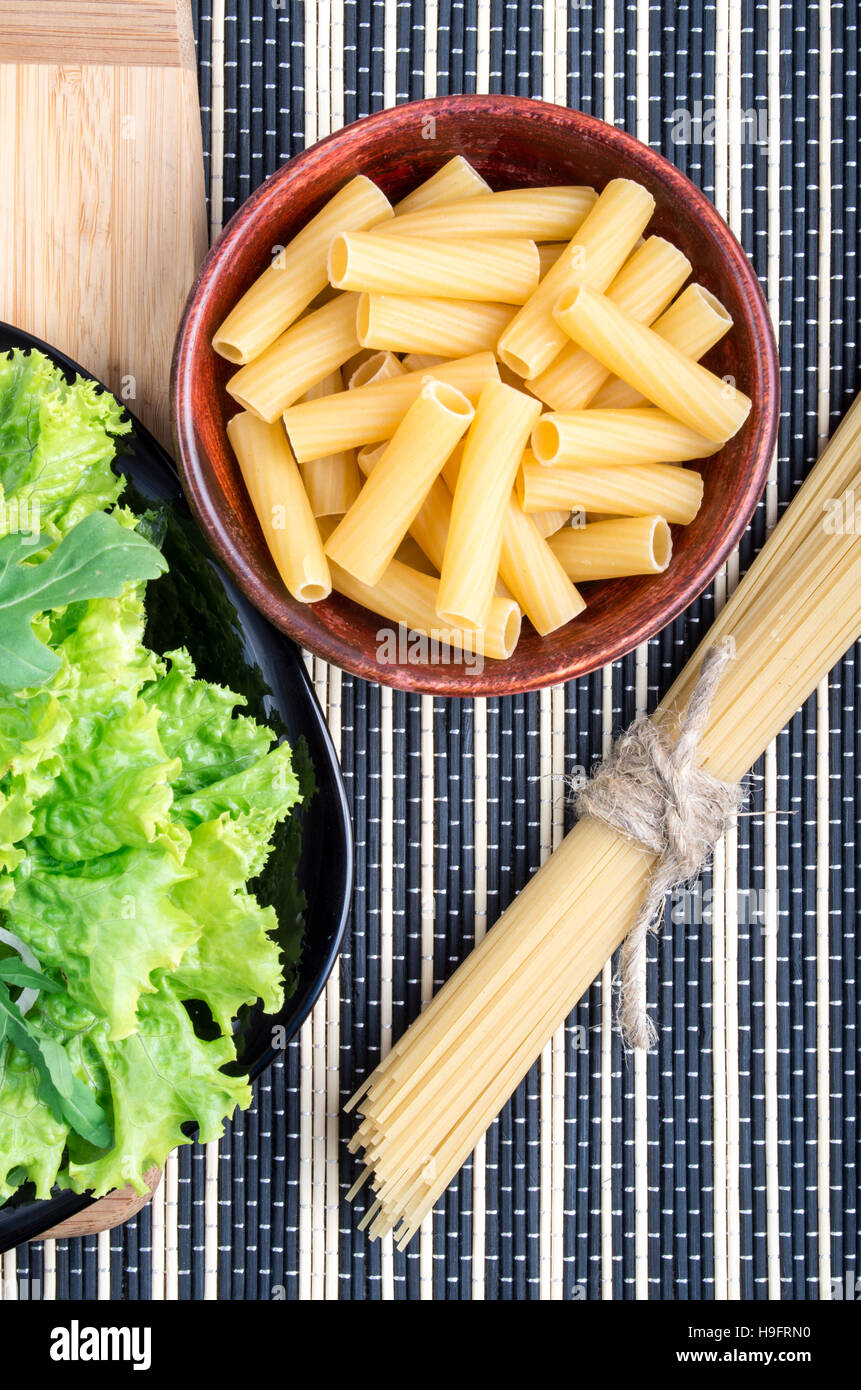Draufsicht auf die Zutaten zum Kochen gesunde Ernährung - Spaghetti, Pasta und Salat auf einem Holzsockel auf der Oberfläche des Tisches Stockfoto