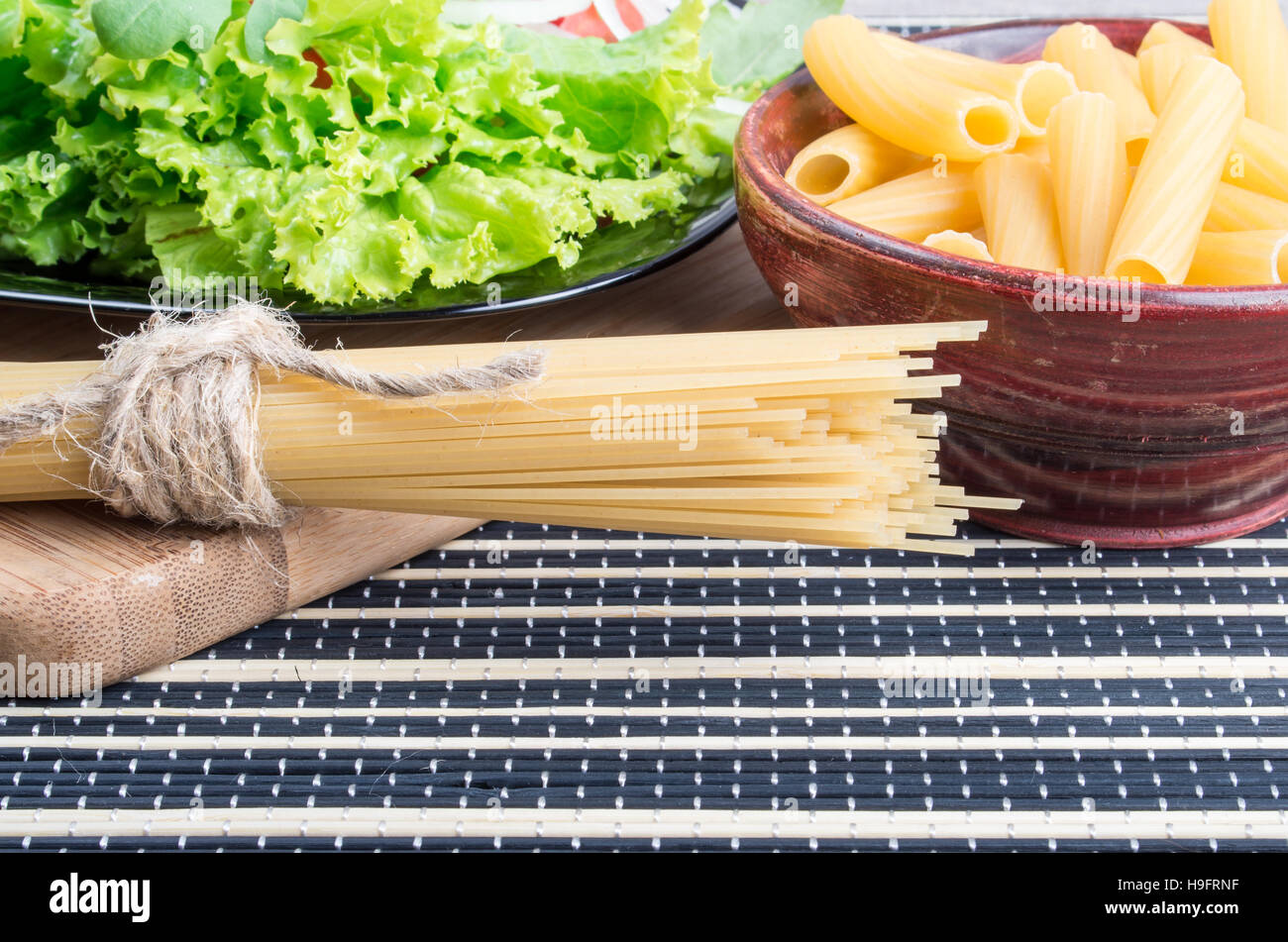 Teigwaren und Spaghetti mit grünem Salat von frischem Gemüse Nahaufnahme auf der Oberfläche der Küchentisch Stockfoto
