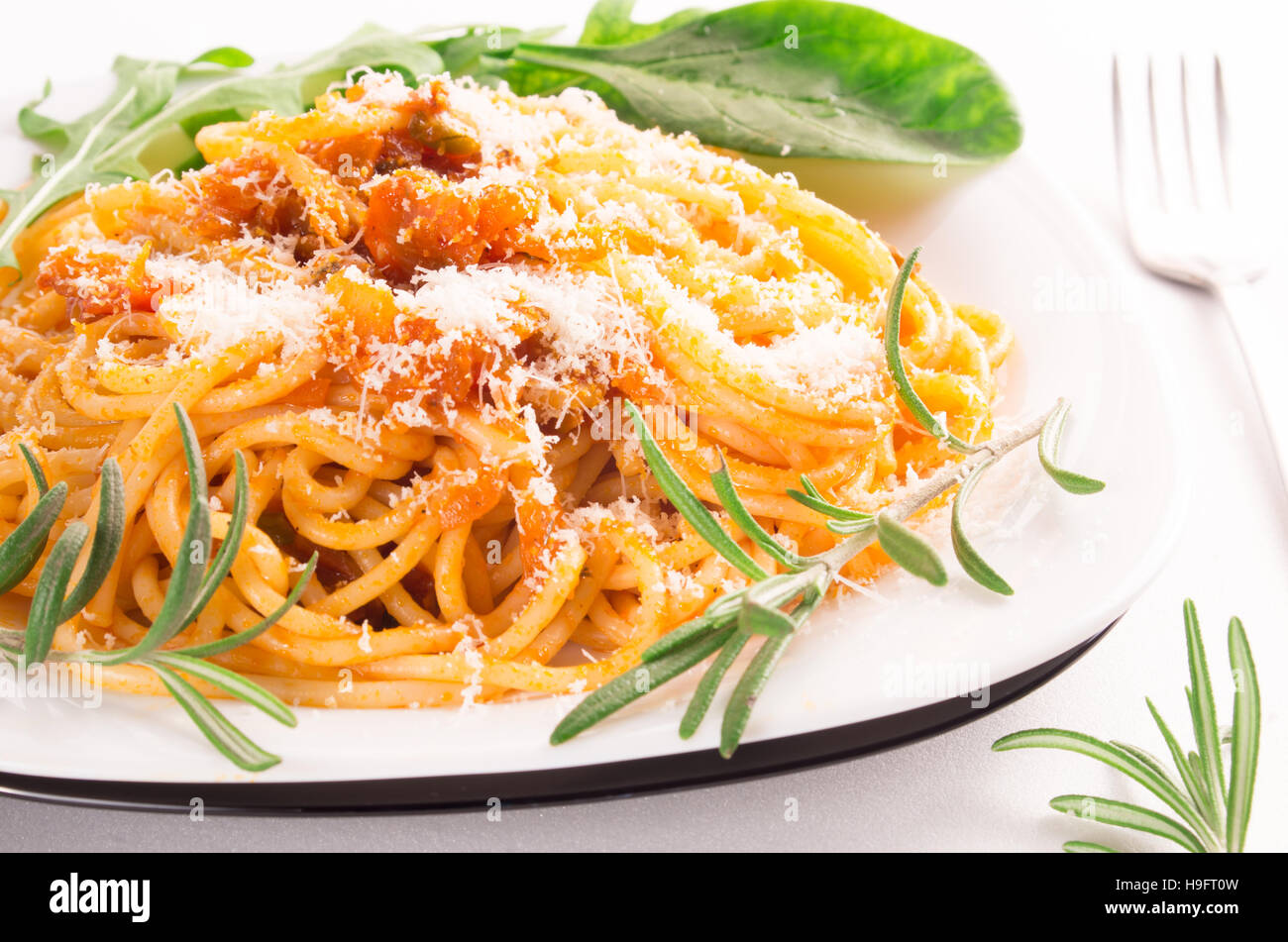 Gekochte Spaghetti mit Gemüse-Sauce, frischen Kräutern und Parmesan auf einem weißen Teller-Nahaufnahme Stockfoto