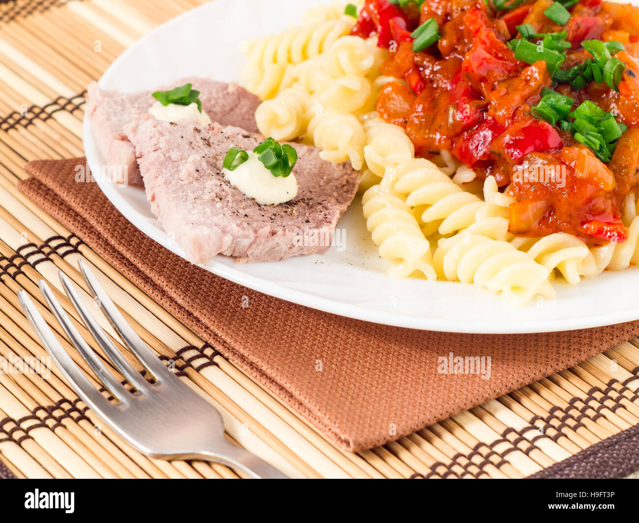 Italienische Pasta mit Gemüse-Sauce und Scheiben von Fleisch mit Kräutern auf eine Platte Nahaufnahme mit geringer Tiefe des Fokus. Stockfoto