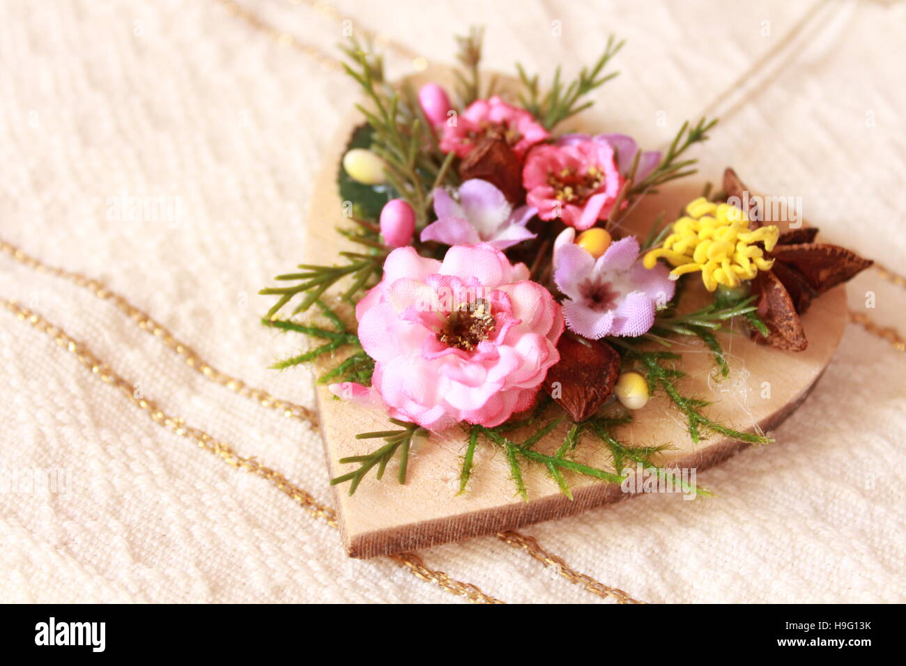 Herz aus Holz, verziert mit künstlichen Blüten sitzen auf einem traditionellen Handtuch Stockfoto