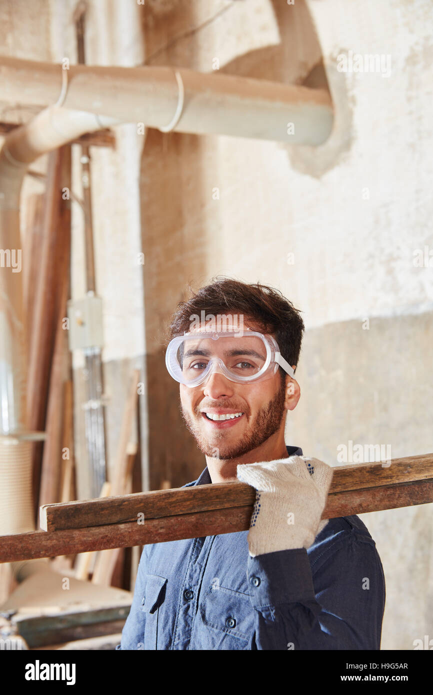 Worker bei Tischlerei lächelnd und Holz tragen Stockfoto
