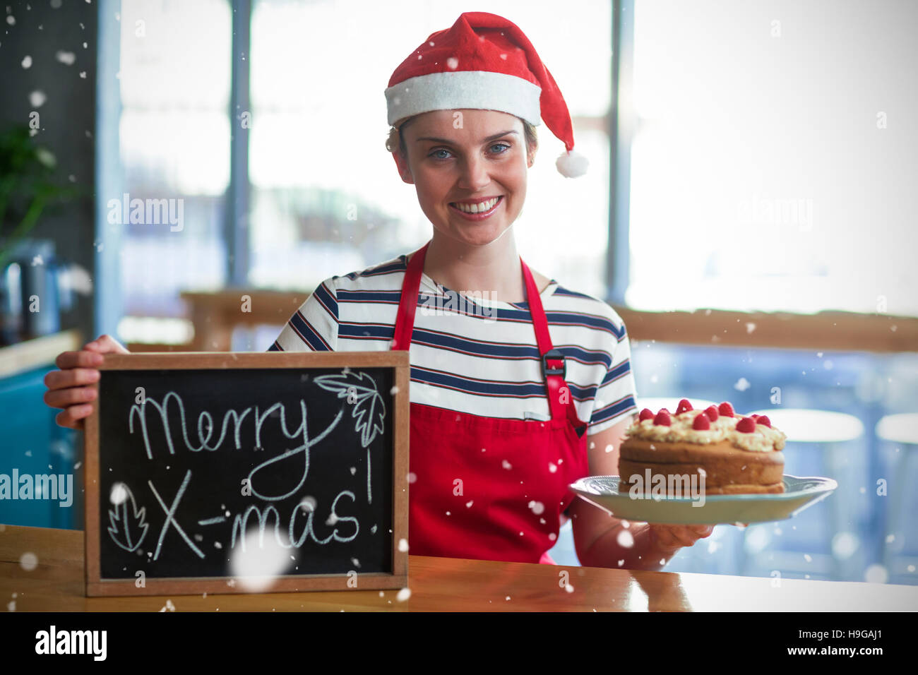 Zusammengesetztes Bild Porträt der Kellnerin mit Schiefer mit merry x-mas-Zeichen und Kuchen Stockfoto