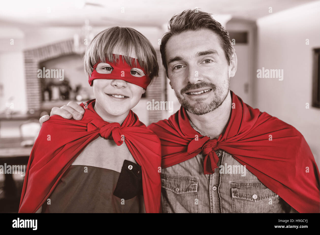 Porträt von Vater und Sohn, die vorgibt, Superheld im Wohnzimmer Stockfoto