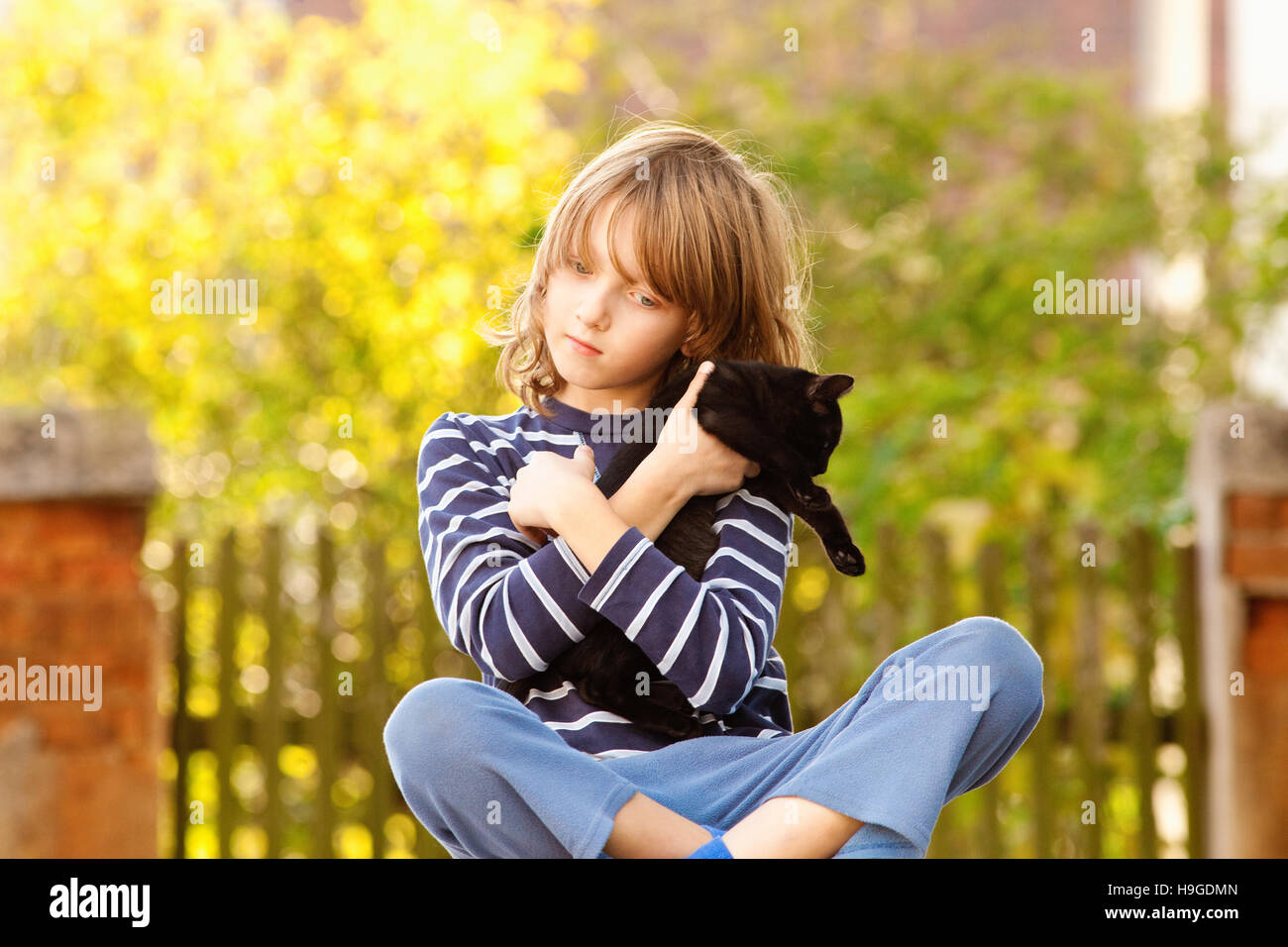 Junge sitzen hält einen Kätzchen Stockfoto