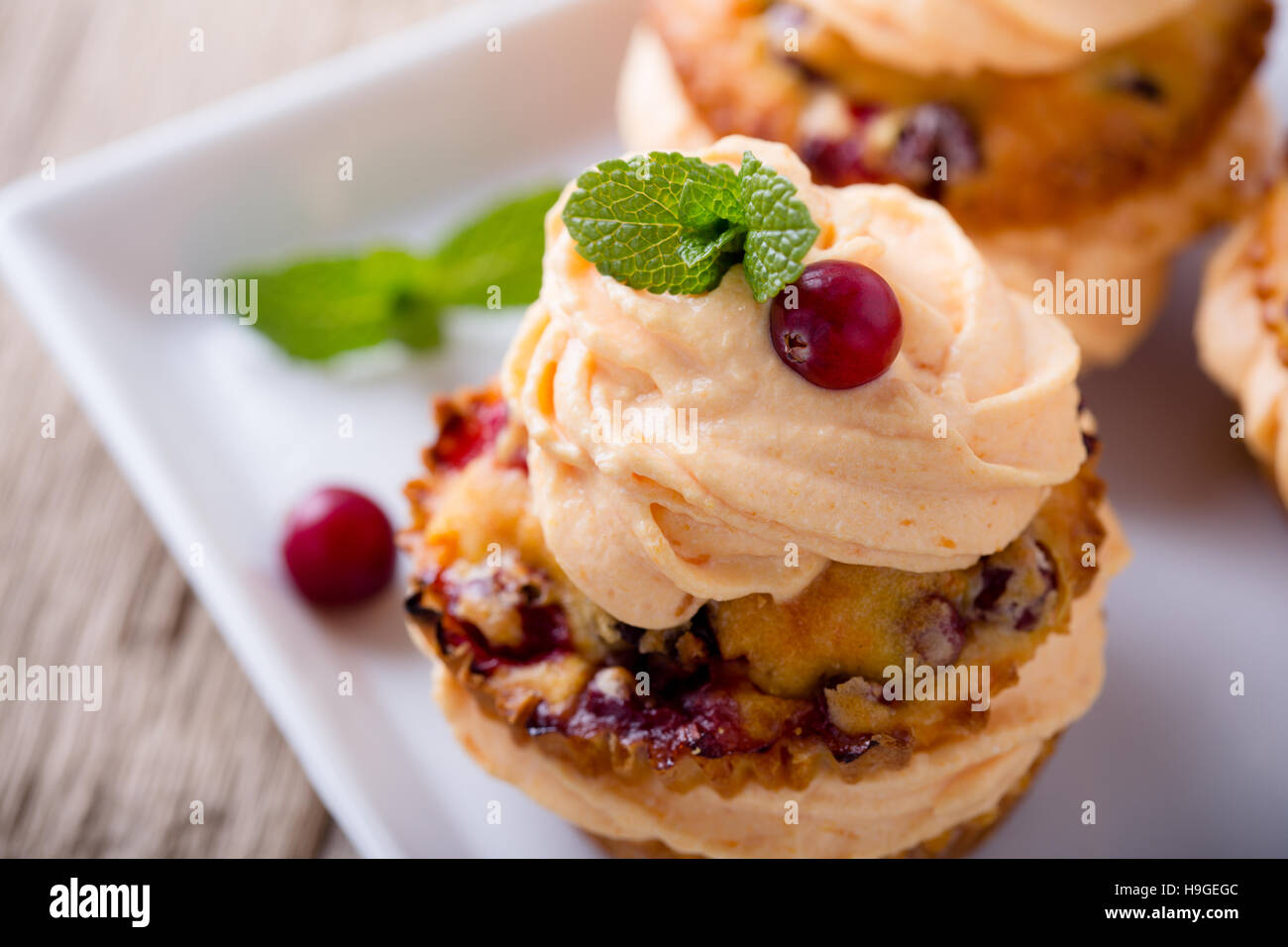 Hausgemachte Herbst Cranberry-Kürbis-Cupcakes mit Frischkäse Icingon rustikalen Holztisch Stockfoto