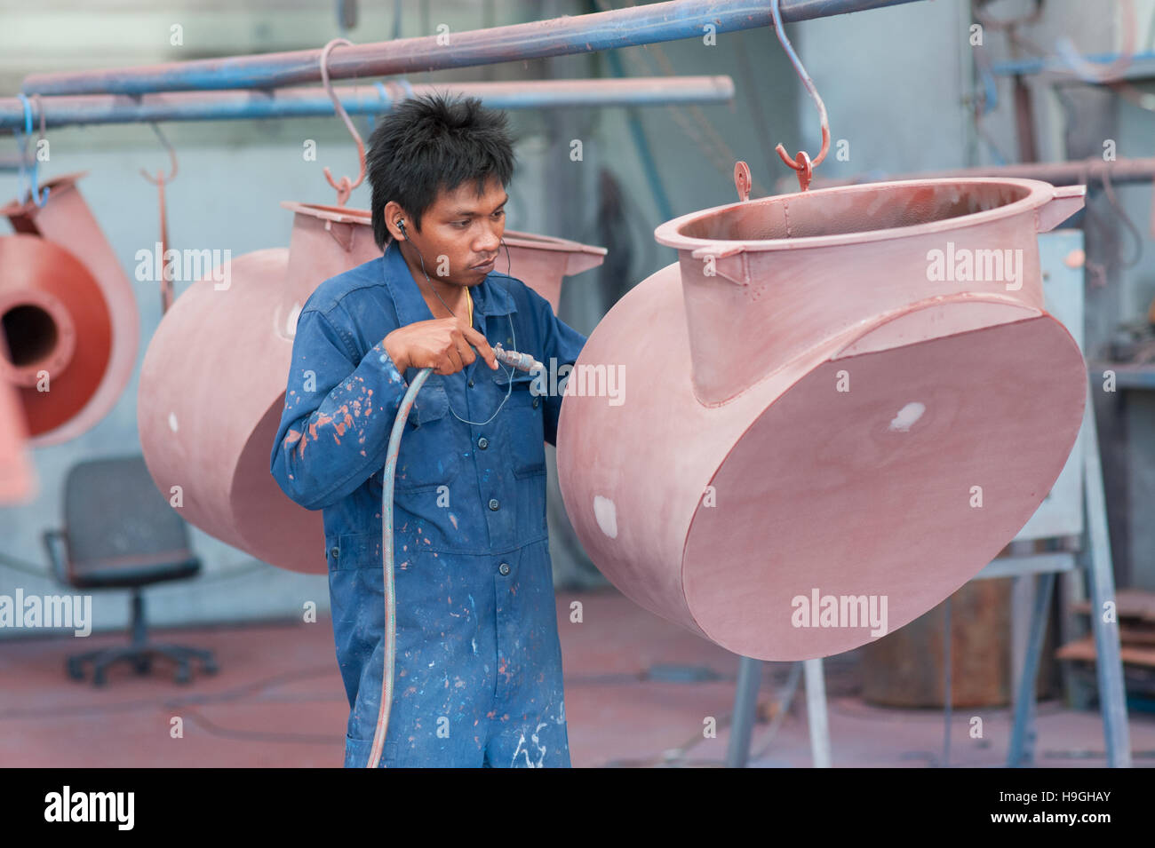 Asiatische (Thai) Worker bei industriellen Lackiererei Reinigung Teile mit Druckluft vor dem Lackieren. Stockfoto