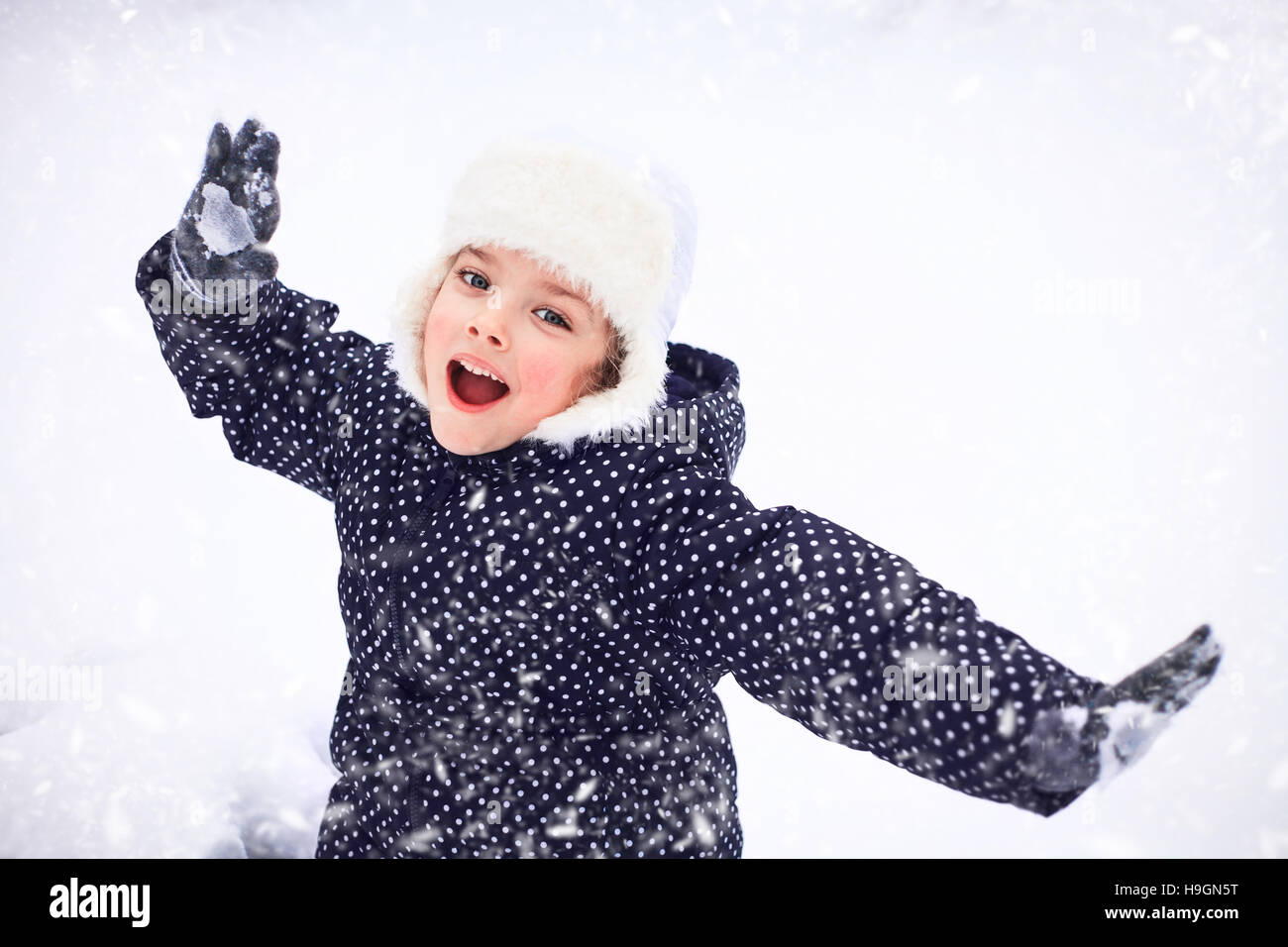 Porträt eines süßen kleinen Mädchens in einem verschneiten Park während eines Schneefalls. Stockfoto