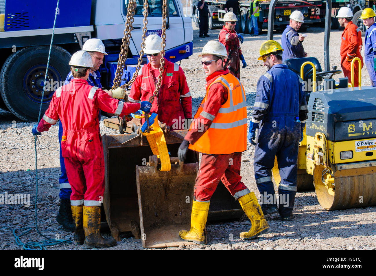 Bauarbeiter bereiten ein Kranhaken, Baggerlader Bagger buckets.at einer explorativen Ölquelle zu heben. Stockfoto