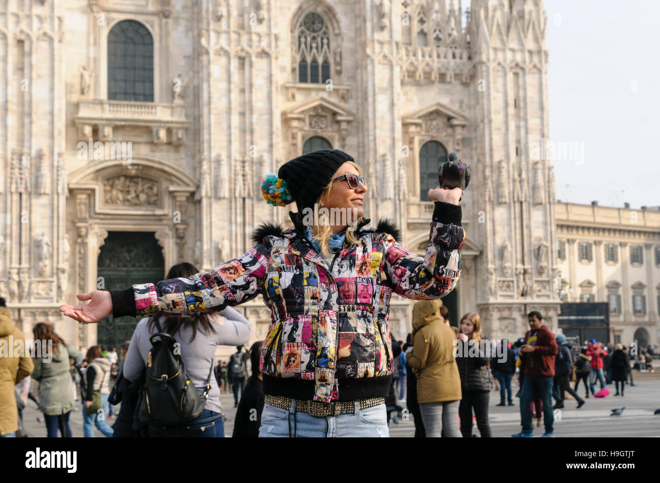 Eine Frau hält Lebensmittel für Tauben auf der Piazza del Duomo, Mailand, Italien Stockfoto