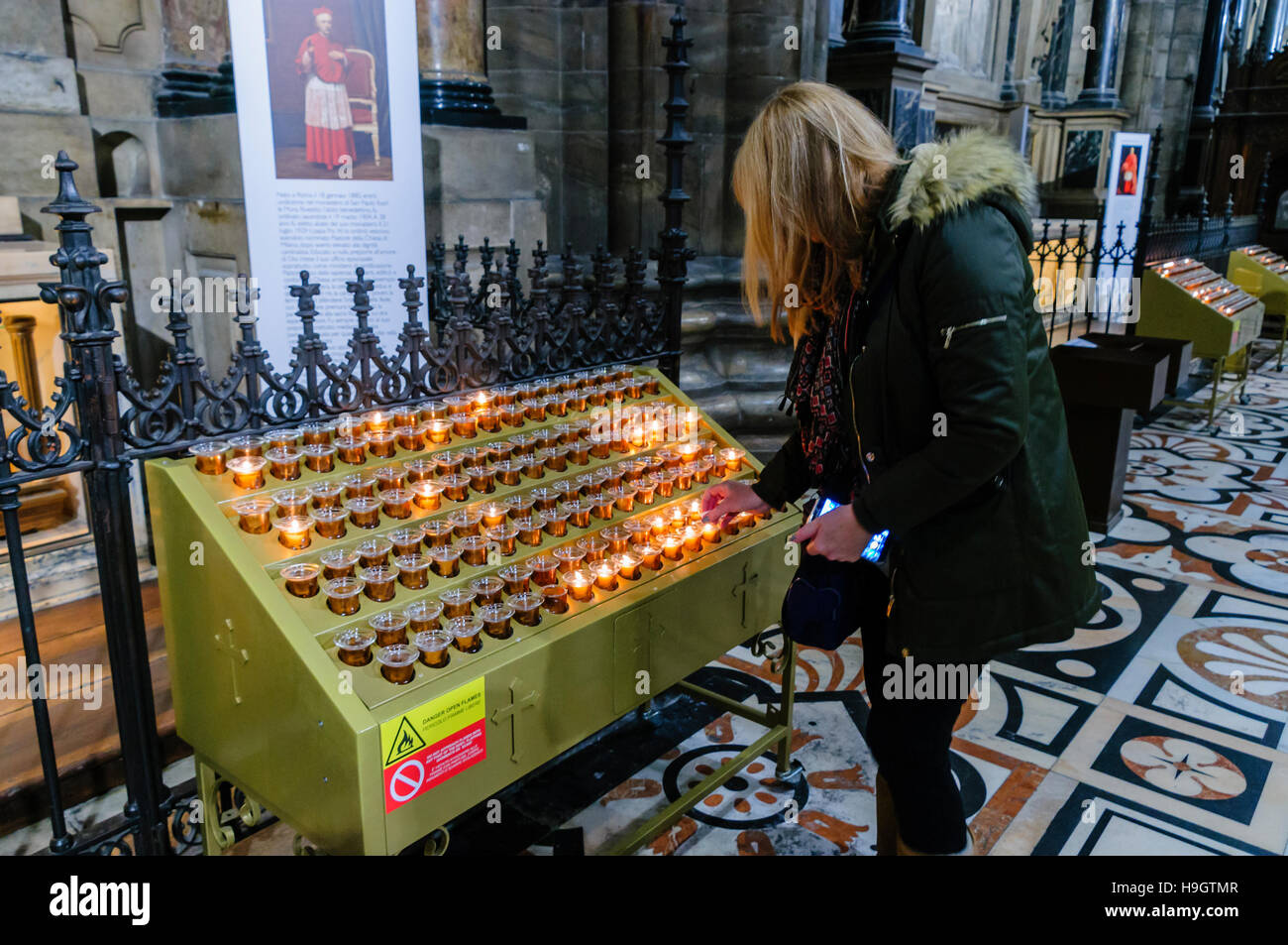 Eine Frau zündet eine Kerze um ein Familienmitglied in der Duomo Milano (Mailand Kathedrale), Italien erinnern. Stockfoto