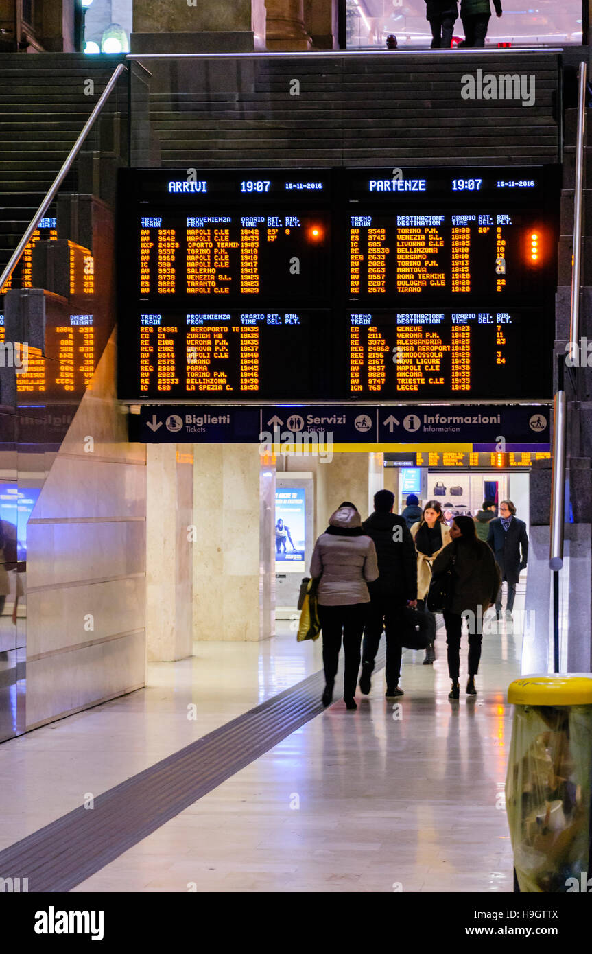 Passagiere Fuß unter dem Zeitplan Brett am Bahnhof Milano Centrale, Mailand, Italien. Stockfoto