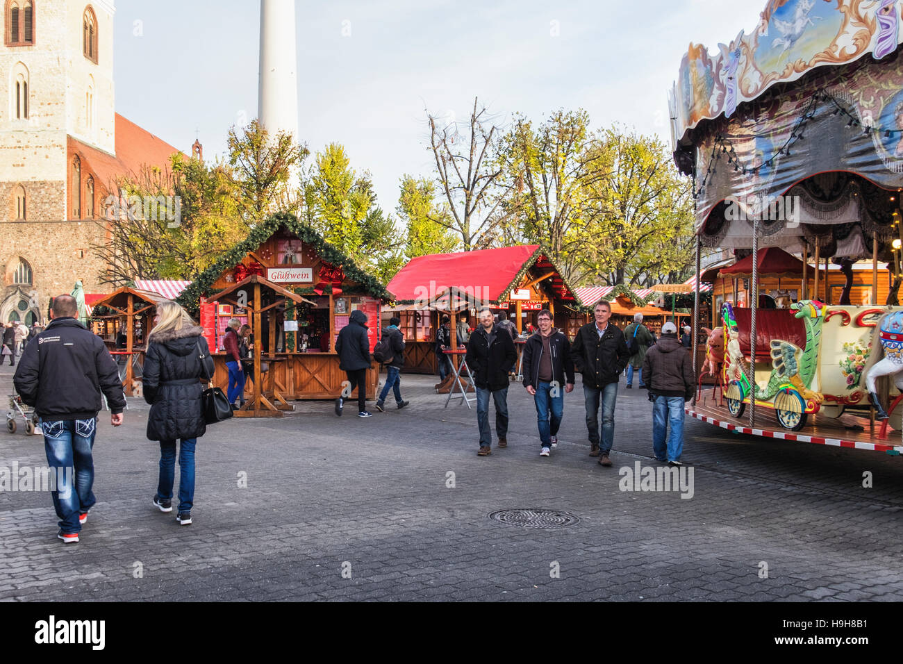 Berlin, Deutschland, 23. November 2016. Die Berliner Weihnachtzeit ist ein deutscher Weihnachtsmarkt rund um den historischen Neptunbrunnen (Neptunbrunnen) hinter Alexanderplatz gelegen. Die festliche hölzerne Marktstände befinden sich zwischen das Rotes Rathaus (Rotes Rathaus) und der Marienkirche. Eine festliche Atmosphäre erfolgt durch Drehorgel Musik, Glühwein, Stände verkaufen Kunsthandwerk, Brot in einer traditionellen Bäckerei und heißen Met gebacken aus Tonkrügen serviert. Besucher genießen eine Eisbahn und das 50 Meter hohe Riesenrad mit traditionellen Gondeln. Kinder genießen Sie Besuche zu den Streichelzoo, Pony zu befreien Stockfoto