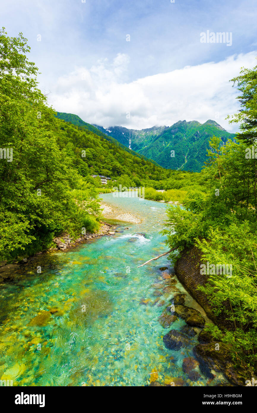 Das kristallklare Wasser von der Azusa Fluss schlängelt sich durch unberührten Wäldern mit Landschaftsansicht der Mount Hotaka-Dake in Kamikochi Stockfoto