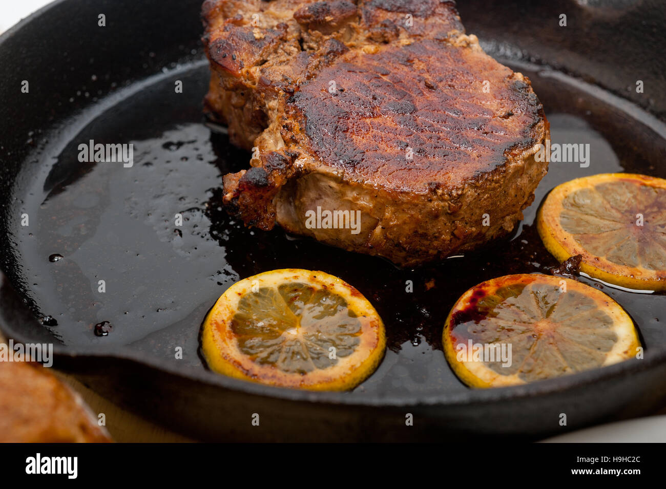 Schweinekotelett auf eisernen Pfanne mit Zitrone und Gewürze Gewürz angebraten Stockfoto