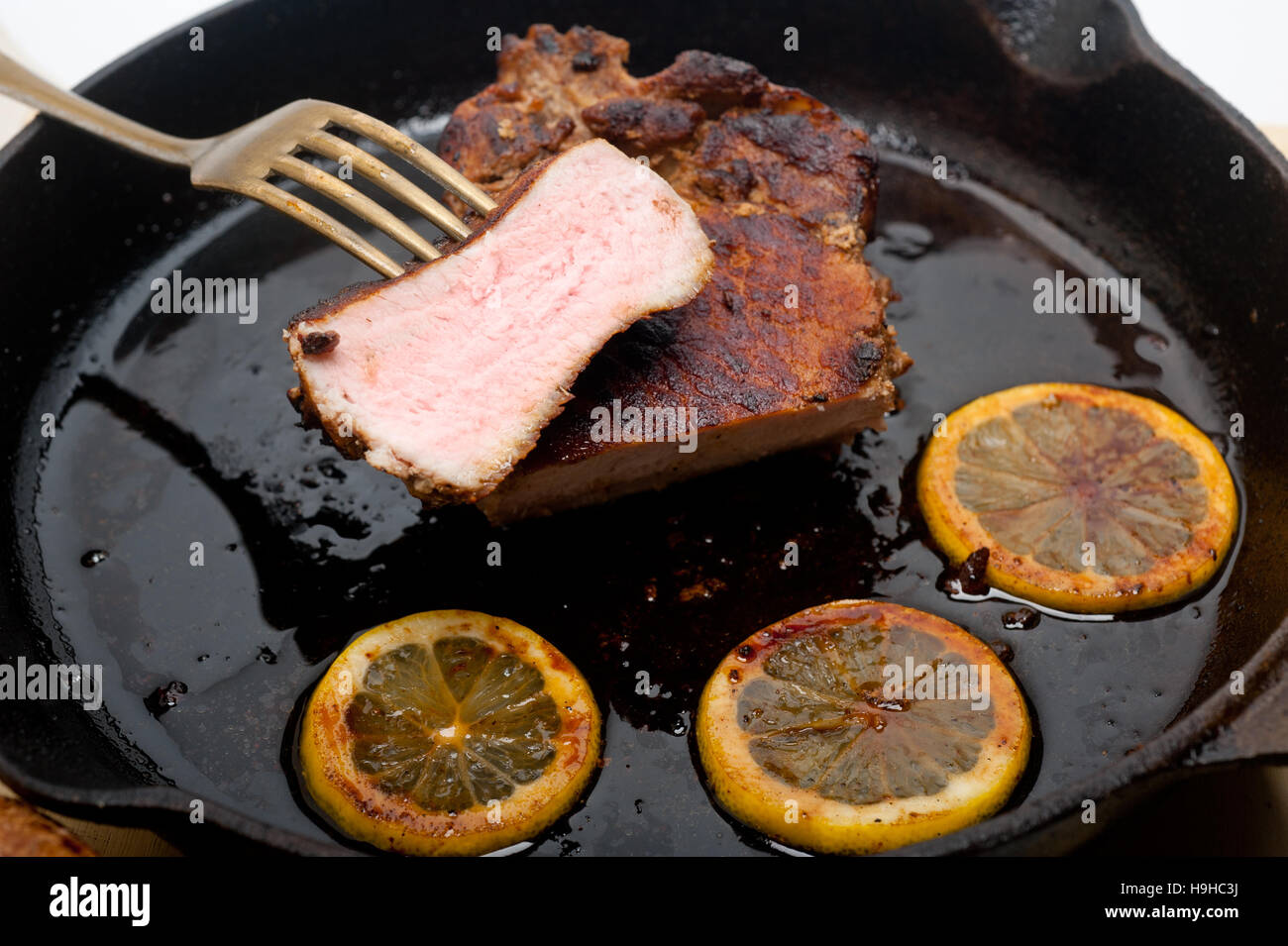 Schweinekotelett auf eisernen Pfanne mit Zitrone und Gewürze Gewürz angebraten Stockfoto