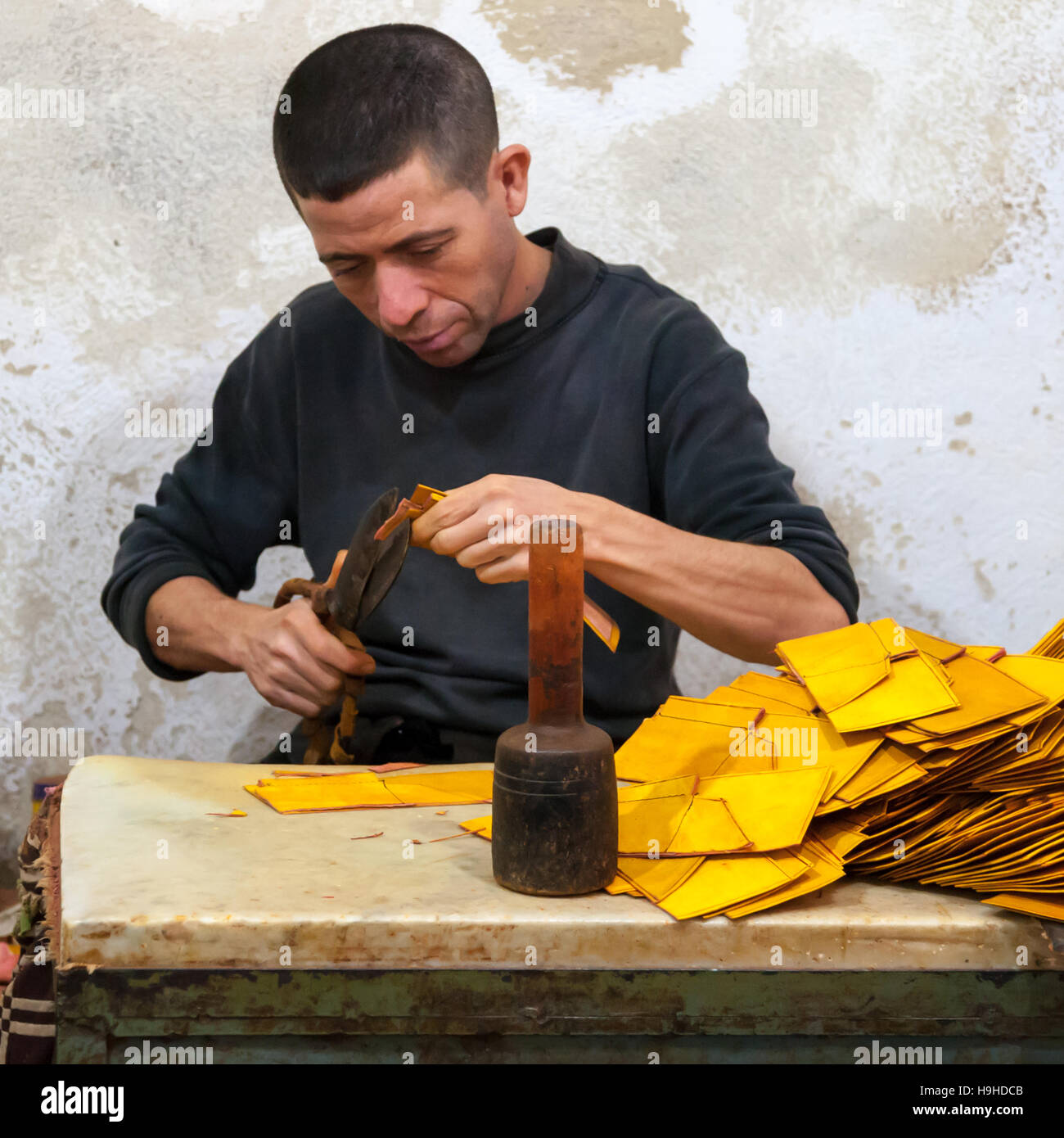 Marokkanischer Handwerker Schneiden von Leder für die Herstellung von Brieftaschen. Am Rande des Gerberviertels in Fès wird das Leder zu Taschen, Schuhen und Kleidung verarbeitet Stockfoto
