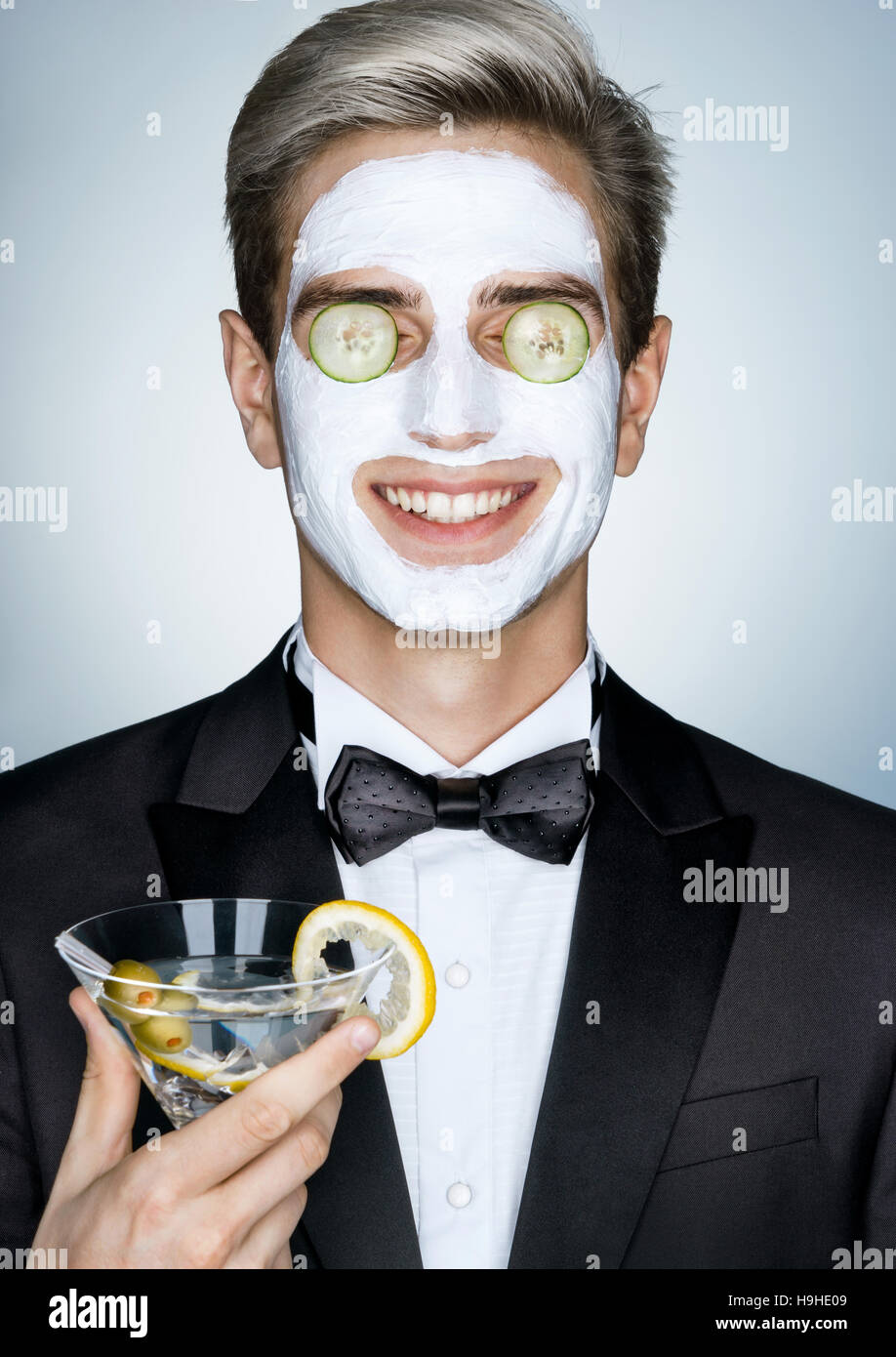 Entspannen Sie sich. Gentleman mit Glas Martini und kosmetische Maske auf dem Gesicht. Foto von stilvollen glücklich erhält die Spa-Behandlungen. Pflege selbst Stockfoto
