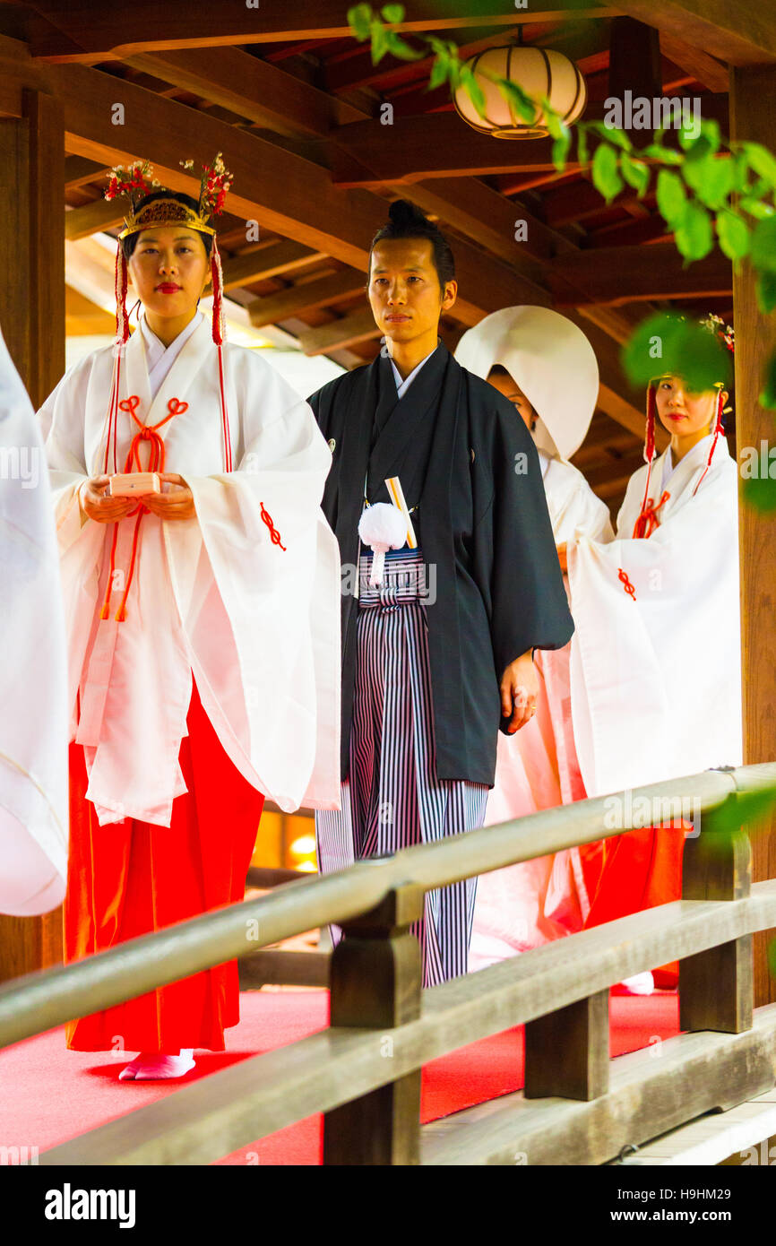 Bräutigam in traditionellen Gewändern zu Fuß mit Jungfrauen, gefolgt von Shinto Hochzeit Braut Brücke am Yushima Tenmangu Schrein Stockfoto