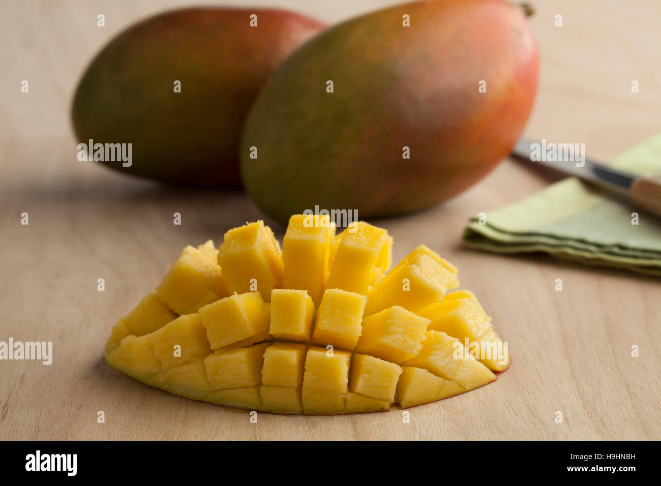 Frische reife saftige halbe gelbe Mango und ganz im Hintergrund Stockfoto
