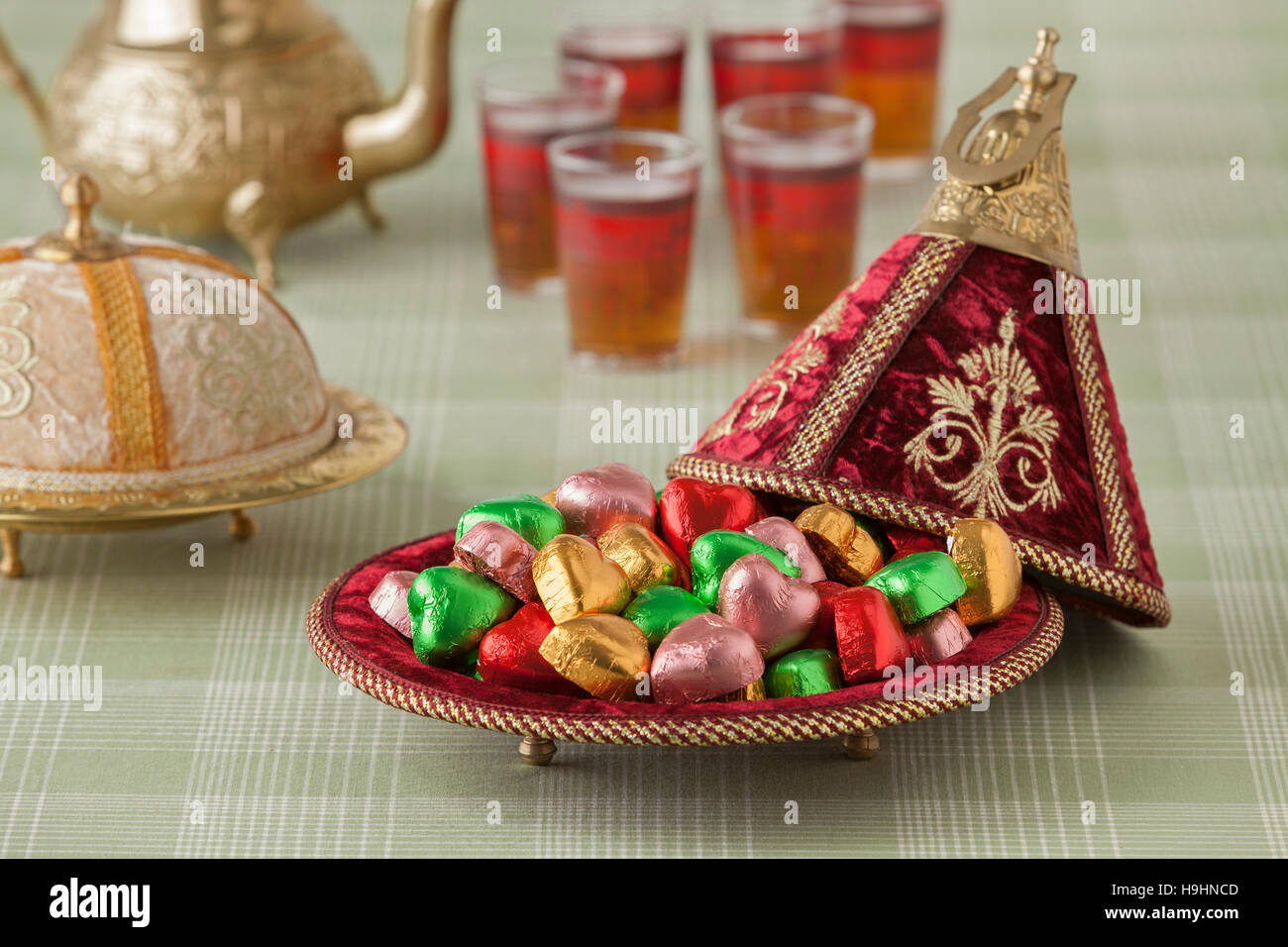 Marokkanische festliche Süßigkeiten in eine rote Tajine und Tee Stockfoto