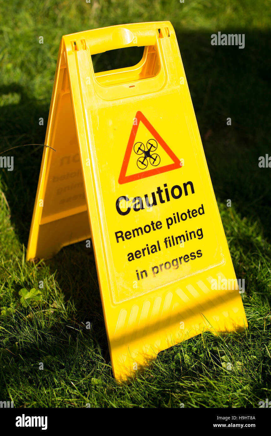 Eine Frame-Sicherheit Warnung der Drohne Betreiber Dreharbeiten Sign. Auf dem Schild steht "Vorsicht. Fernbedienung gesteuert Antenne Dreharbeiten im Gange. Stockfoto