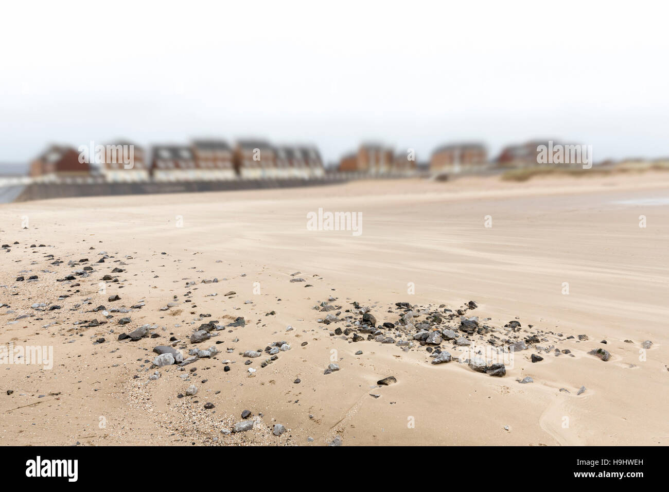 Kieselsteine am Sandstrand mit Strandpromenade Häuser, Aberavon, Wales, UK Stockfoto