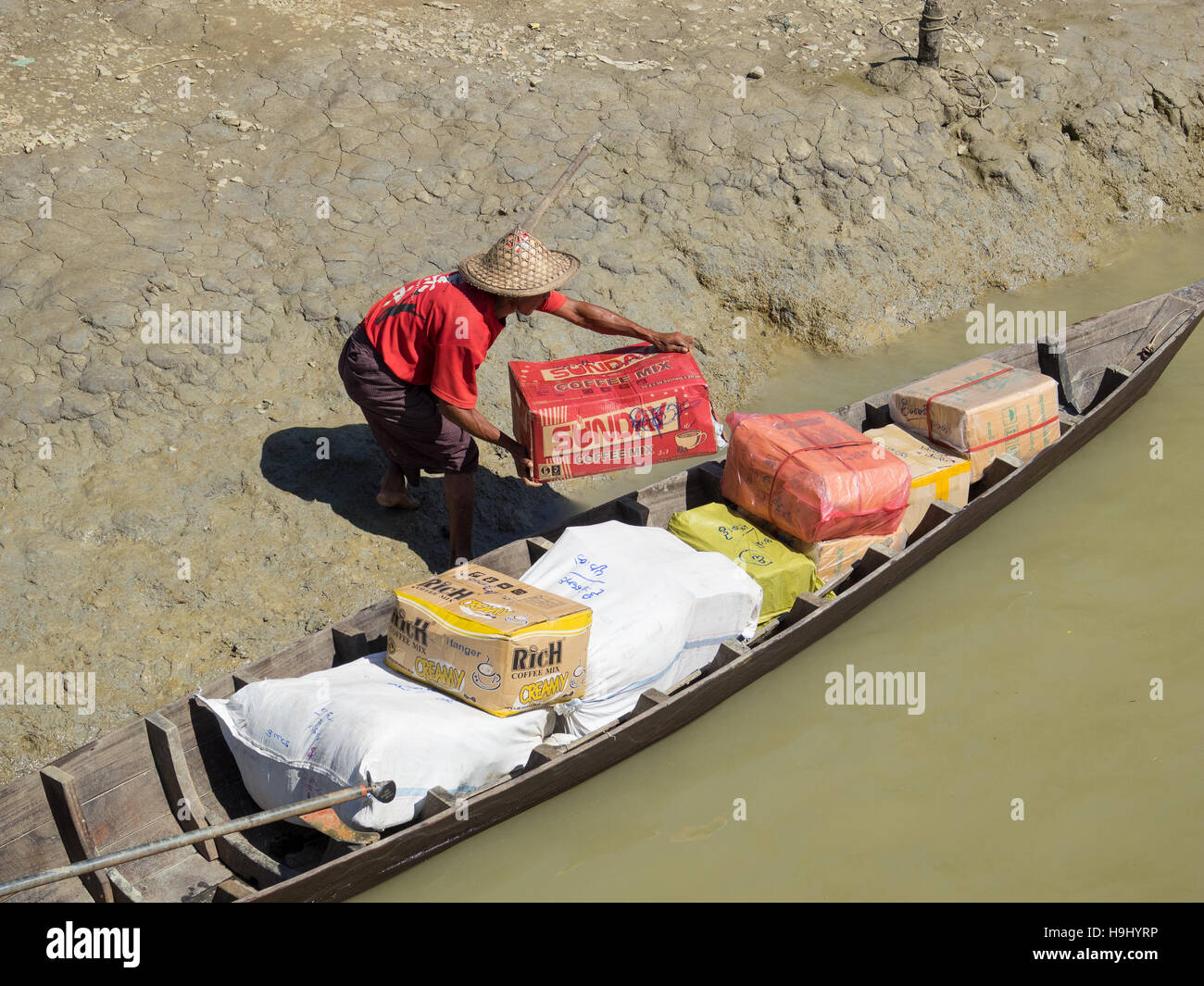 Waren der Verladung in ein kleines Boot für die lokale Verteilung entlang der Nebenflüsse des Flusses Kaladan in Myanmar. Stockfoto