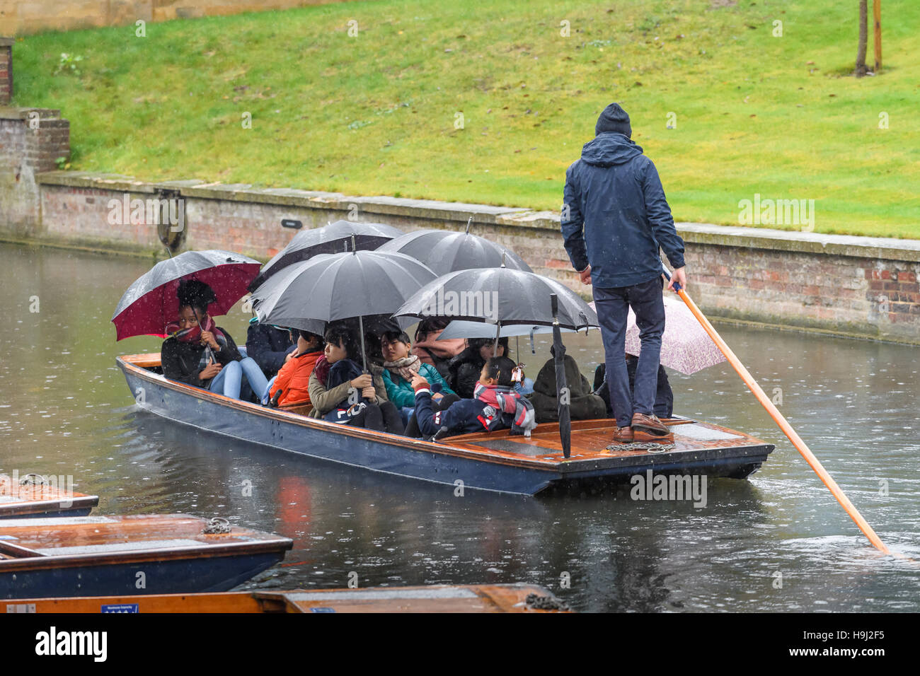 Touristen machen Sie einen Ausflug in einem Kahn entlang des Flusses Cam an einem regnerischen Tag in Cambridge, England. Stockfoto