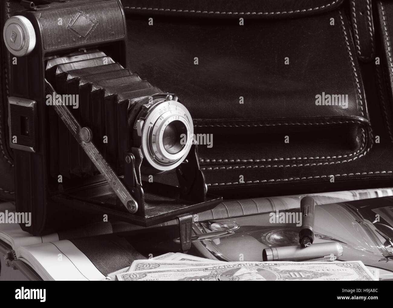 Vintage-Kamera, Leder Aktentasche, Stift und Geld über Auto Bild, alle aus der fünfziger Jahre Ära Stockfoto