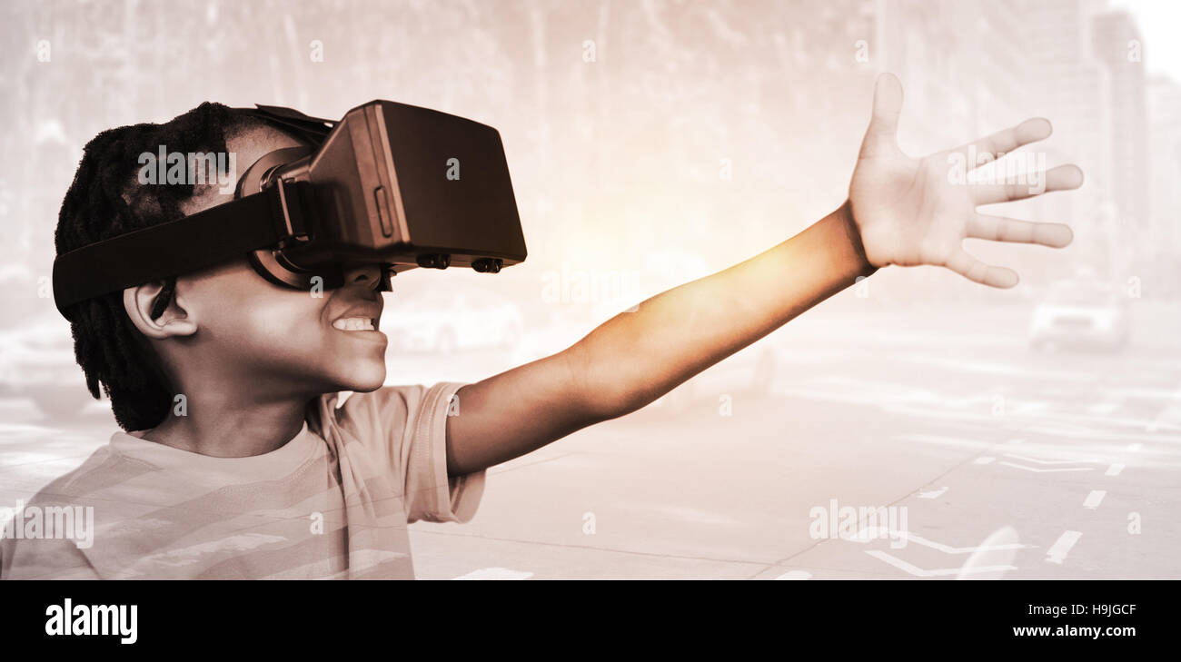 Zusammengesetztes Bild der Seitenansicht des kleinen Jungen halten virtuelle Brille auf weißem Hintergrund Stockfoto
