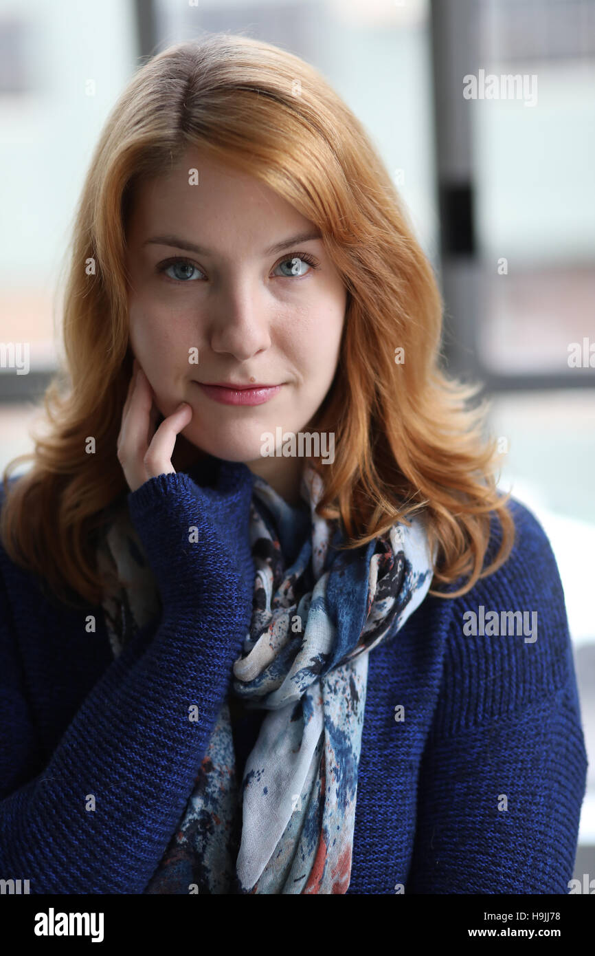 Schuss in den Kopf von eine sehr attraktive junge Frau mit roten Haaren und wunderschönen blauen Augen. Sie trägt einen blauen Schal und Pullover. Stockfoto