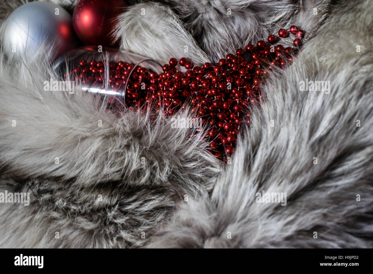 Graues Fell und Weihnachtskugeln Stockfoto