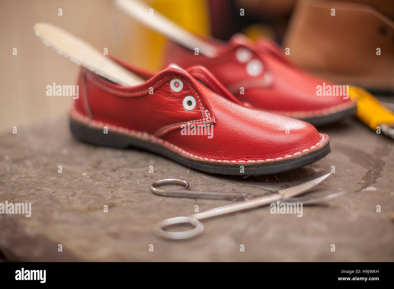 Unvollendete rote Schuhe in Schusterwerkstatt Stockfoto