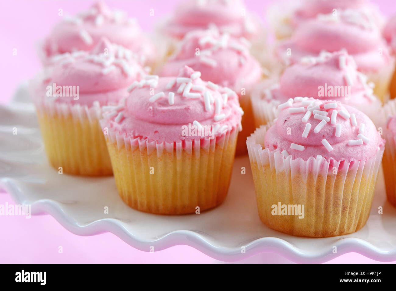 Zarte süße Mini Erdbeer Muffins auf weißen Sockel Kuchen stehen auf rosa Hintergrund im Querformat.  Geringe Schärfentiefe. Stockfoto