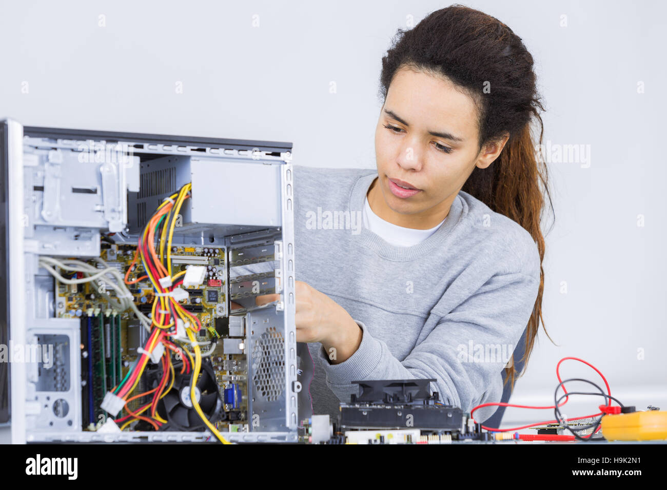 junge Frau, die versucht, einen Computer zu reparieren Stockfoto