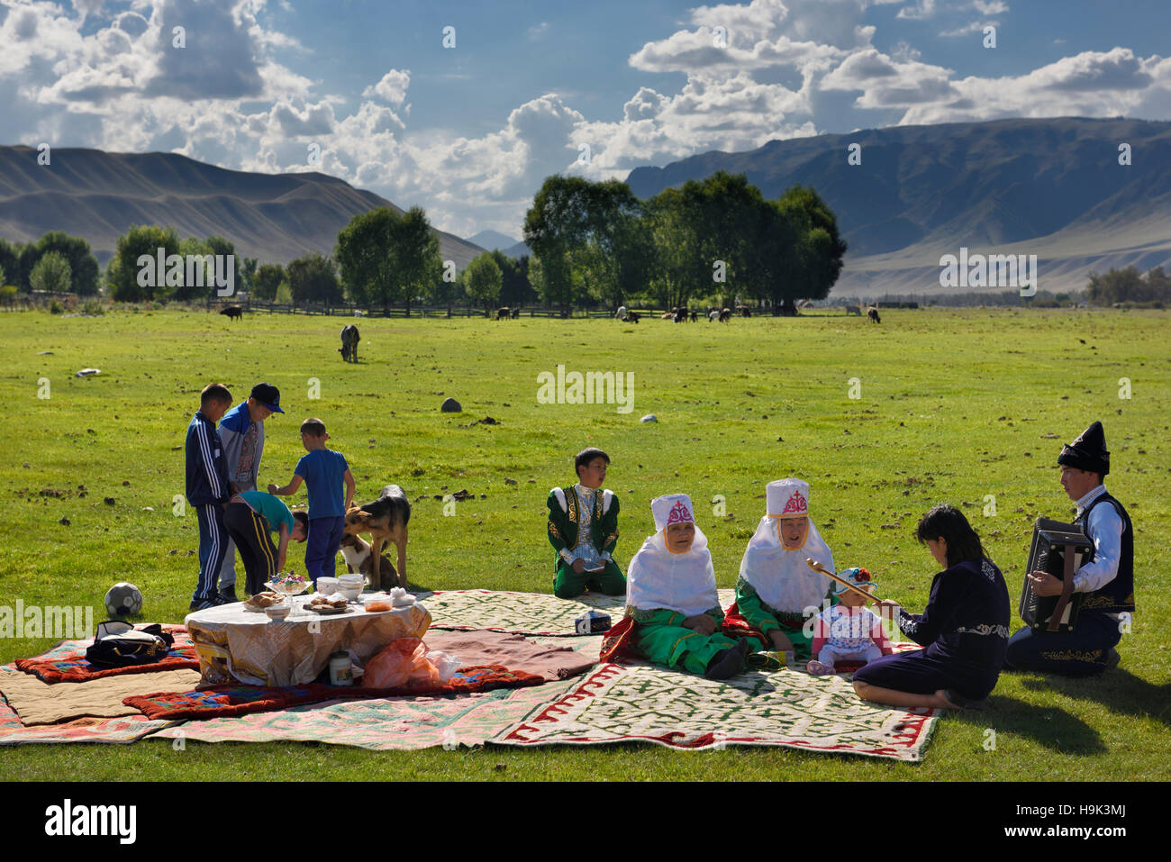 Picknick mit der Familie in traditioneller Kleidung in bleib Weiden am Fluss Chilik Kasachstan singen Stockfoto