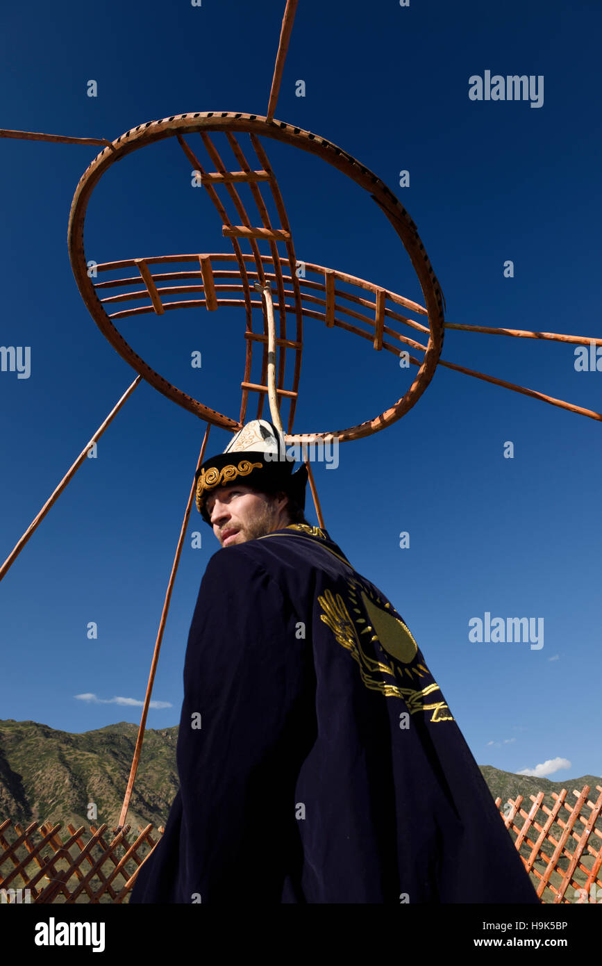 Mann in traditioneller Kleidung hält die Holzdach Krone für eine Jurte in bleibt Kasachstan Stockfoto
