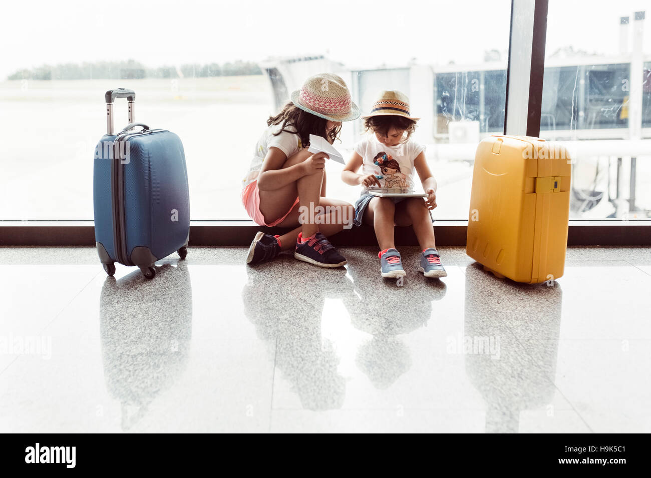 Zwei kleine Mädchen warten am Flughafen, mit digital-Tablette zu spielen Stockfoto