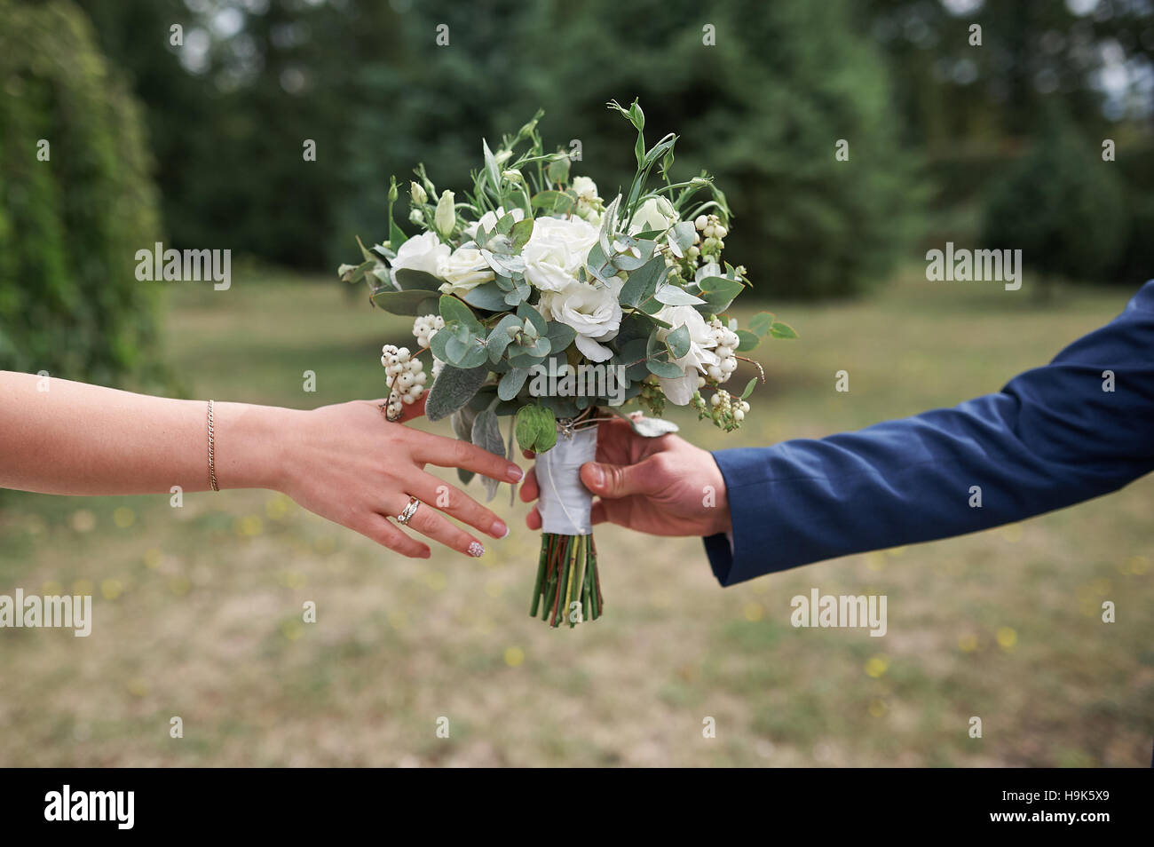 Bräutigam gibt der Braut einen wunderschönen Brautstrauß auf dem Spaziergang Stockfoto