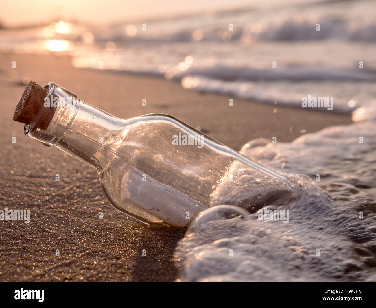 Die Flaschenpost angeschwemmt gegen die untergehende Sonne nach unten Stockfoto