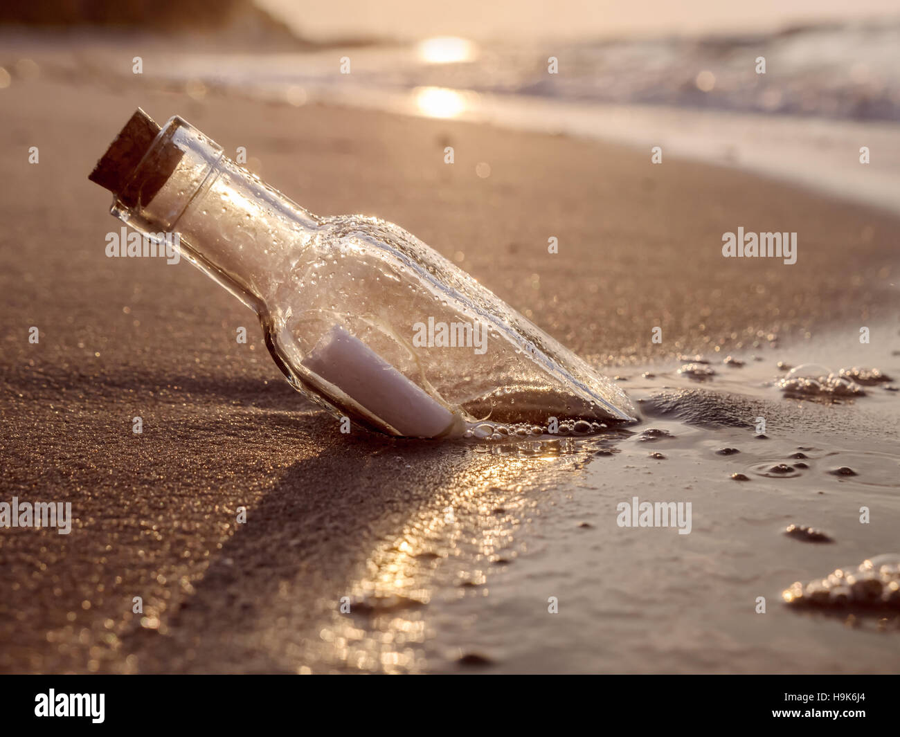 Die Flaschenpost angeschwemmt gegen die untergehende Sonne nach unten Stockfoto